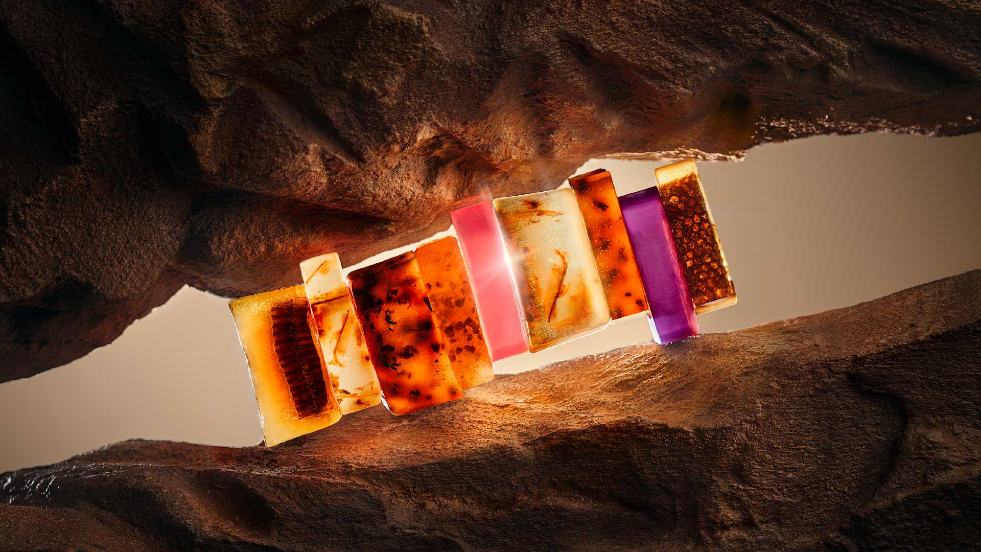 Row of translucent handmade STENDERS soaps glowing between amber-toned rocks