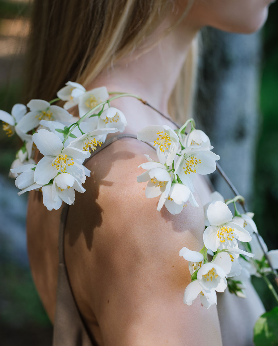 Jasmine blossoms resting across a woman's shoulder in soft daylight